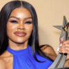 Woman with long black hair in a blue halter top posing with a star-shaped trophy in hand.