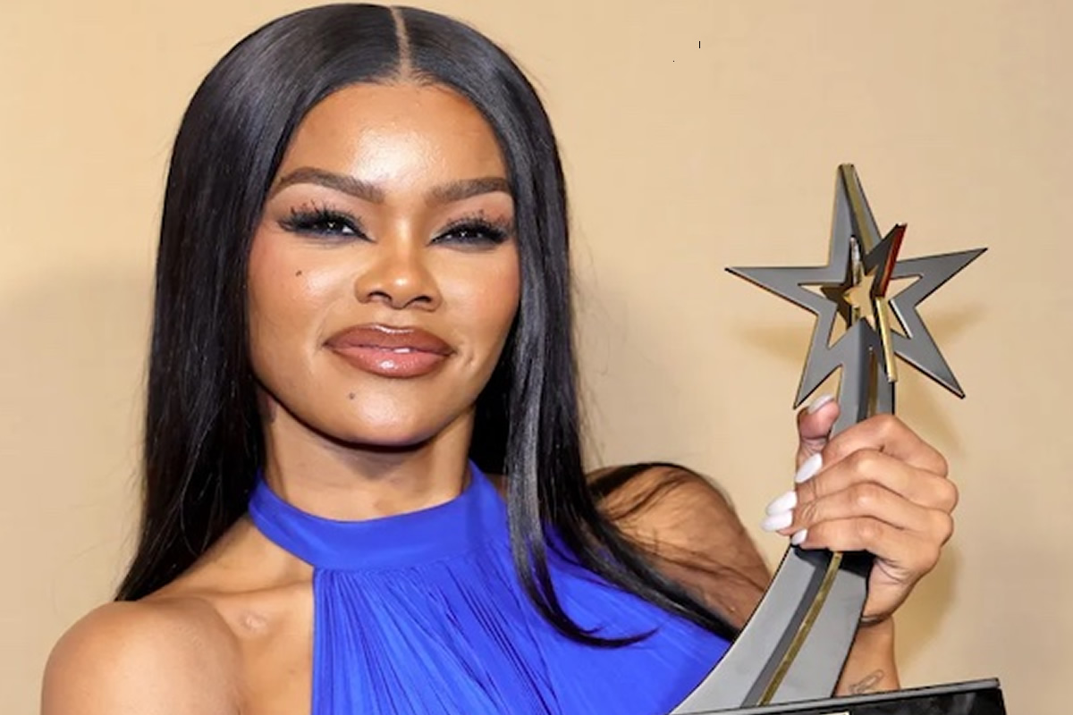 Woman with long black hair in a blue halter top posing with a star-shaped trophy in hand.