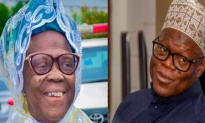 Smiling elderly woman in a blue lace headwrap and glasses (left) and an elderly man in a patterned kufi hat and dark shirt (right).