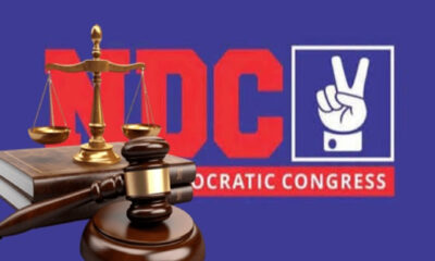 Scales of justice and judge's gavel in front of a red 'DC' logo and 'Democratic Congress' text on a blue background.