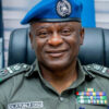 Colonel Olatunji Disu in a green dress uniform with ribbons and a blue beret, smiling at the camera.