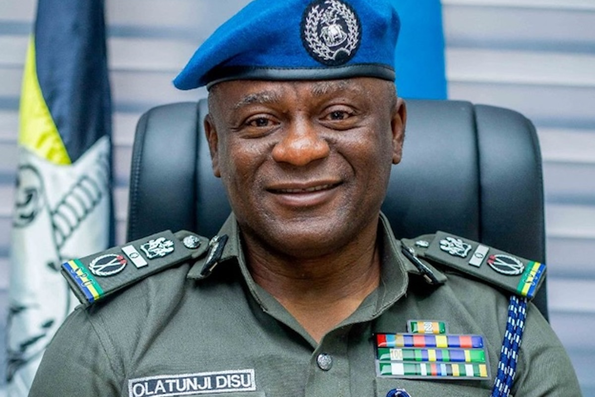 Colonel Olatunji Disu in a green dress uniform with ribbons and a blue beret, smiling at the camera.