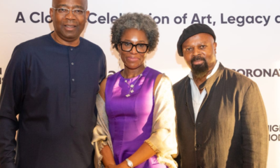 Three people pose for a photo at an art celebration event, with a banner behind them that reads 'Modernism... A Celebration of Art, Legacy'.