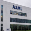 ASML corporate building with a large blue ASML logo on a white facade and glass windows outside.