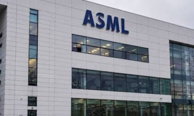 ASML corporate building with a large blue ASML logo on a white facade and glass windows outside.