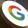 Round white circular sign displaying Google's multicolor G logo (red, yellow, green, blue) on a wooden stand