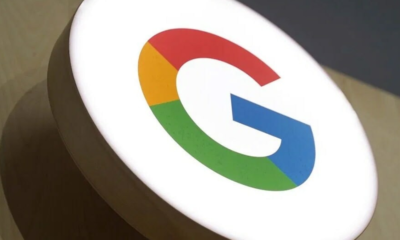 Round white circular sign displaying Google's multicolor G logo (red, yellow, green, blue) on a wooden stand