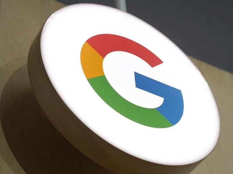 Round white circular sign displaying Google's multicolor G logo (red, yellow, green, blue) on a wooden stand