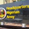 Signboard for the Nigerian Army headquarters, with yellow text on a dark wall and a circular crest emblem