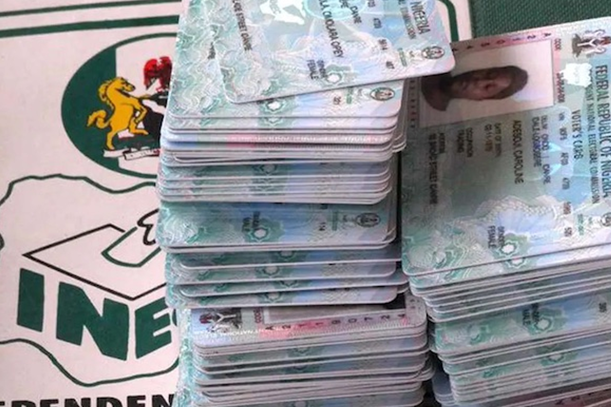 Two tall stacks of Nigerian 100-naira banknotes on a table beside an INEC banner.