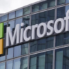 Microsoft logo on a glass-front office building with a red, green, blue, and yellow square icon to the left of the sign.