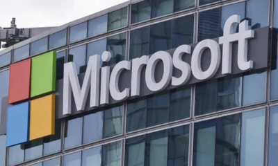 Microsoft logo on a glass-front office building with a red, green, blue, and yellow square icon to the left of the sign.