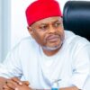A man wearing a red fez and white traditional attire sits at a desk, looking to his left with a thoughtful, concerned expression.