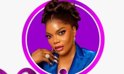 Glamour portrait of a woman with braided updo, bold makeup, wearing a blue blazer and large rings, inside a purple ring frame.
