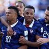 French national team players in blue jerseys celebrate together on the field.