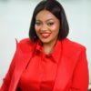 Smiling woman with a black bob haircut wearing a red blazer and blouse against a light background photographed for a professional headshot.