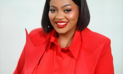 Smiling woman with a black bob haircut wearing a red blazer and blouse against a light background photographed for a professional headshot.