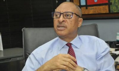 Professional man in a light blue shirt and red striped tie sits in an office chair, hands clasped as he speaks.