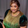 Smiling woman in a gold-and-green sequin dress with matching gold jewelry during a formal photoshoot
