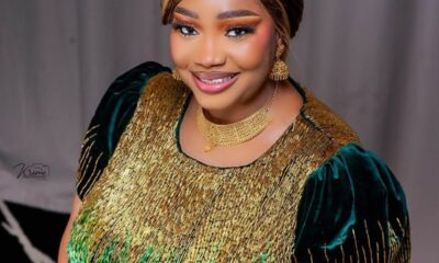 Smiling woman in a gold-and-green sequin dress with matching gold jewelry during a formal photoshoot