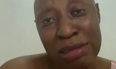 Close-up of a person with a shaved head looking at the camera, wearing a pink sleeveless top, with a calm expression.