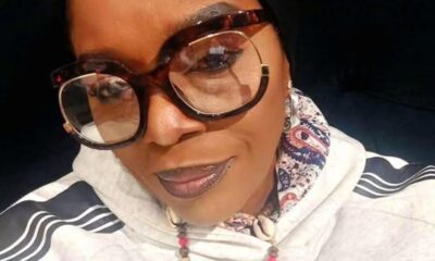 Close-up portrait of a woman wearing oversized round glasses, a head scarf, and a beaded necklace.