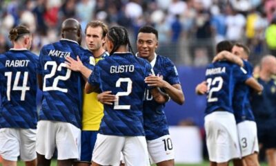 Group of blue-jersey soccer players celebrate on the field, embracing after a game.