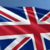 Union Jack flag waving on a flagpole against a clear blue sky (British flag)