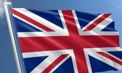 Union Jack flag waving on a flagpole against a clear blue sky (British flag)