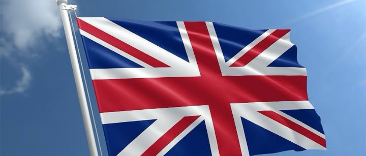 Union Jack flag waving on a flagpole against a clear blue sky (British flag)