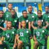 Nigeria women's national football team posing for a group photo on the pitch in green uniforms; goalkeeper in purple on the left.