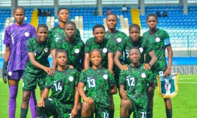 Nigeria women's national football team posing for a group photo on the pitch in green uniforms; goalkeeper in purple on the left.