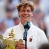 Wimbledon champion smiling while holding the ornate trophy and speaking into a microphone