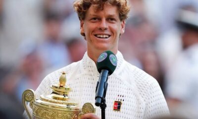 Wimbledon champion smiling while holding the ornate trophy and speaking into a microphone