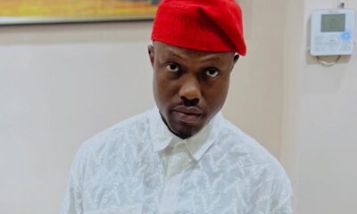 Man wearing a red fez-style hat and white patterned shirt, posing indoors.