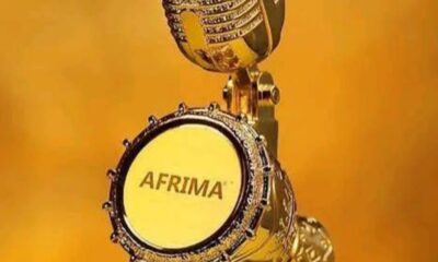 Golden microphone trophy with AFRIMA logo on the mic face against a gold background, close-up.