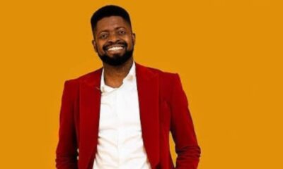 Smiling man in a red blazer and white shirt against an orange background.