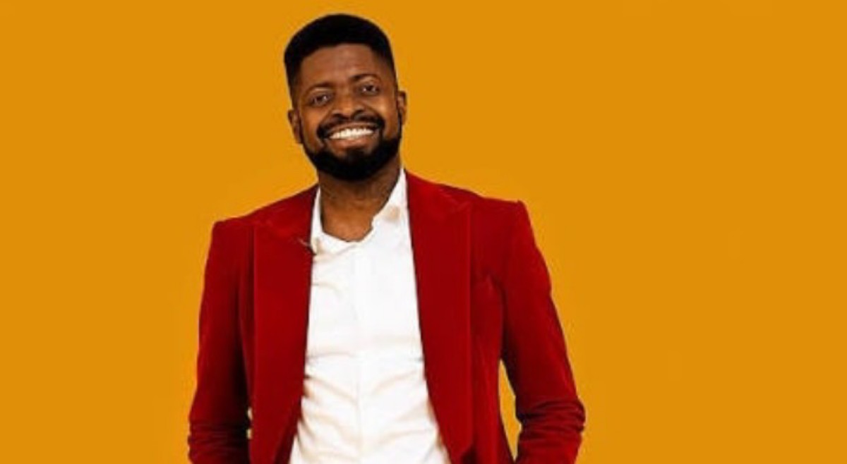 Smiling man in a red blazer and white shirt against an orange background.