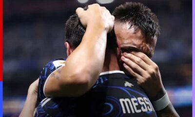 Two soccer players embrace in a celebratory hug on the pitch; the back of one jersey reads MESSI.