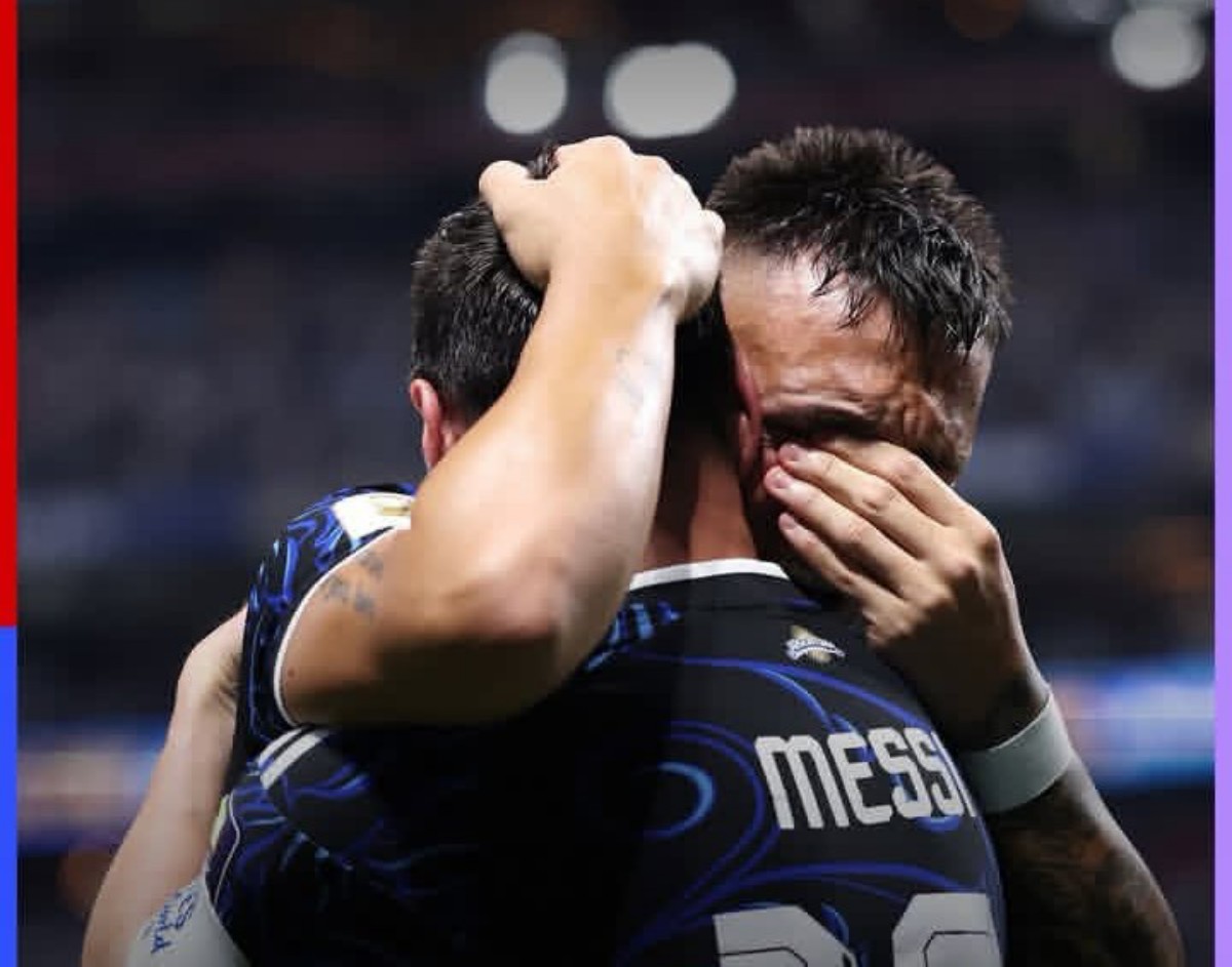 Two soccer players embrace in a celebratory hug on the pitch; the back of one jersey reads MESSI.