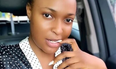 Close-up of a woman sitting in a car, wearing a black and white polka dot blouse, with her hand near her mouth and a soft smile toward the camera.