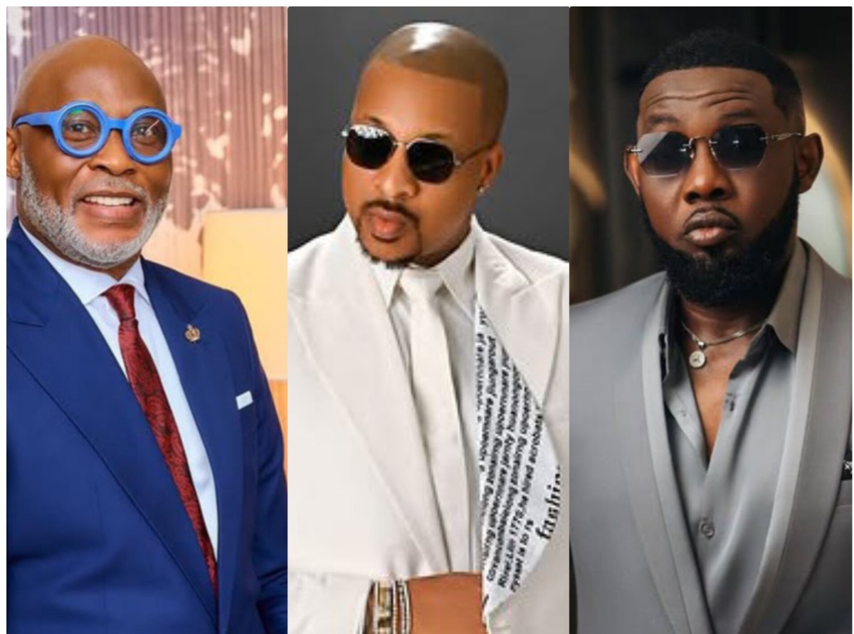Three men in fashionable suits wearing sunglasses: left in blue suit and bright blue round glasses, smiling; center in white suit with patterned scarf and dark sunglasses; right in gray suit with a beard and aviator-style sunglasses.
