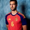 Male model wearing a red Spain national team jersey (number 6) with blue sleeves, standing against a blue textured backdrop.