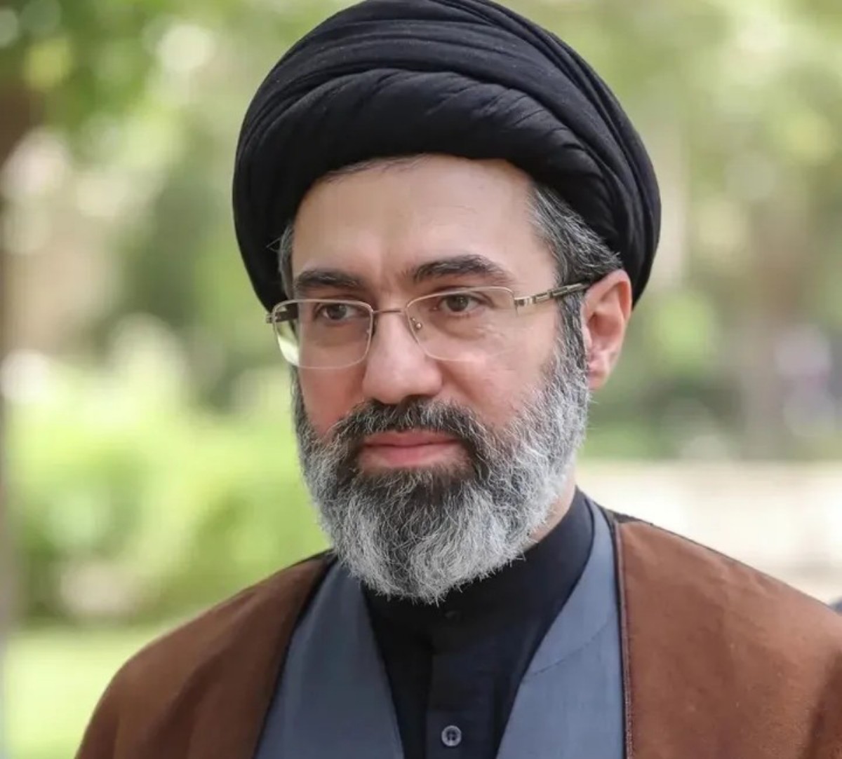 Portrait of a middle-aged man with a black turban, glasses, and gray beard outdoors.