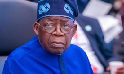 Older man in a bright blue traditional outfit and matching cap, looking to the side in a meeting room setting.
