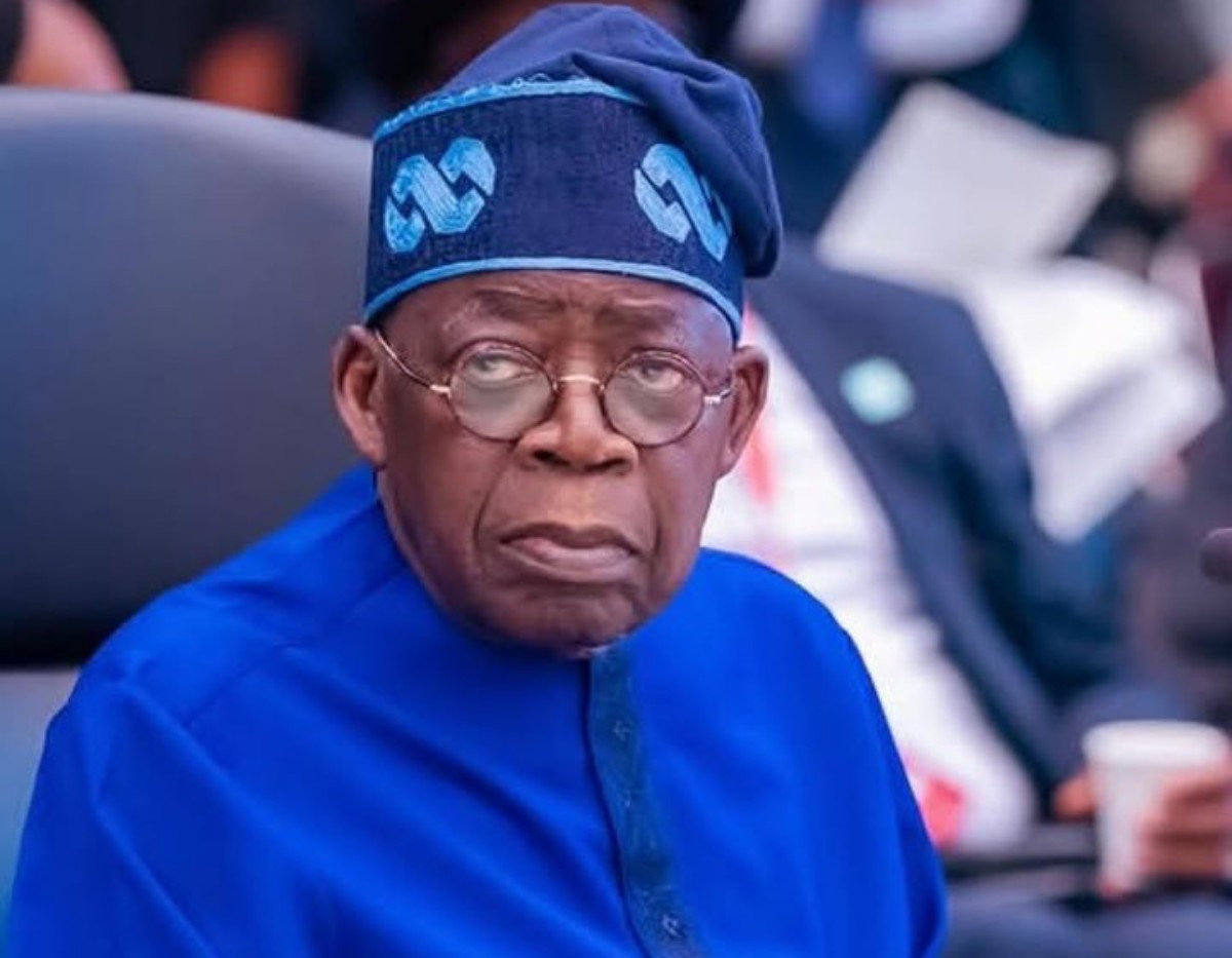 Older man in a bright blue traditional outfit and matching cap, looking to the side in a meeting room setting.