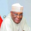 Smiling man wearing a white traditional cap and robe, looking at the camera.