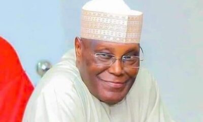 Smiling man wearing a white traditional cap and robe, looking at the camera.