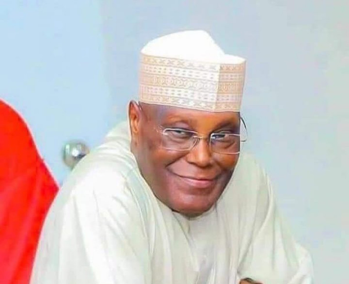 Smiling man wearing a white traditional cap and robe, looking at the camera.