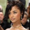 Young woman with short wet-look hair, diamond teardrop earrings, and a gold necklace at a red-carpet event.